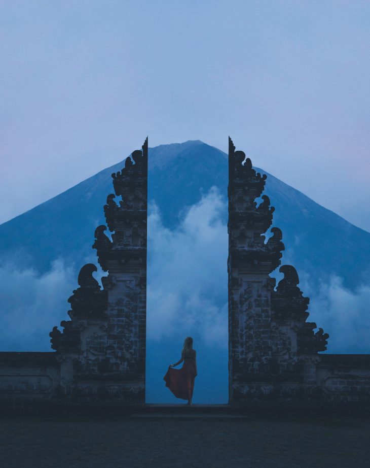 Woman in between on concrete landmarks near white clouds