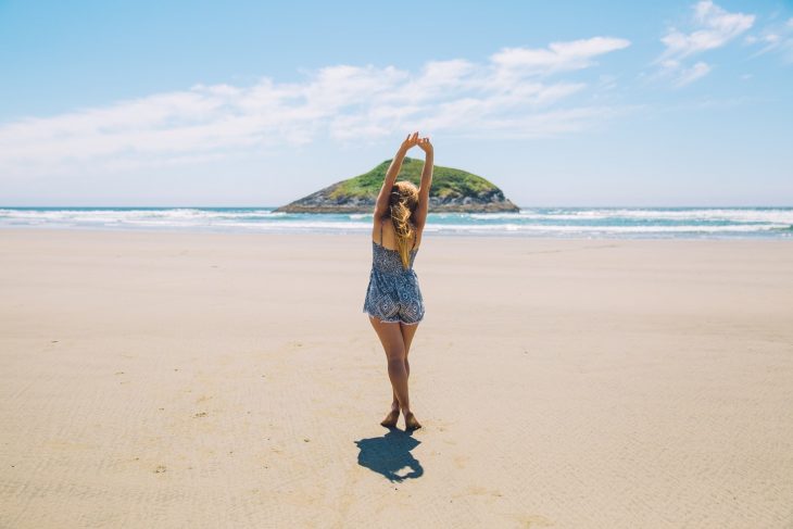 Woman on seashore near island under blue sky